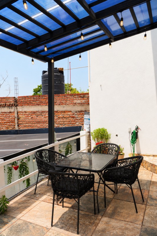 Terraza en la azotea con pérgola de techo azul, mesa y cuatro sillas